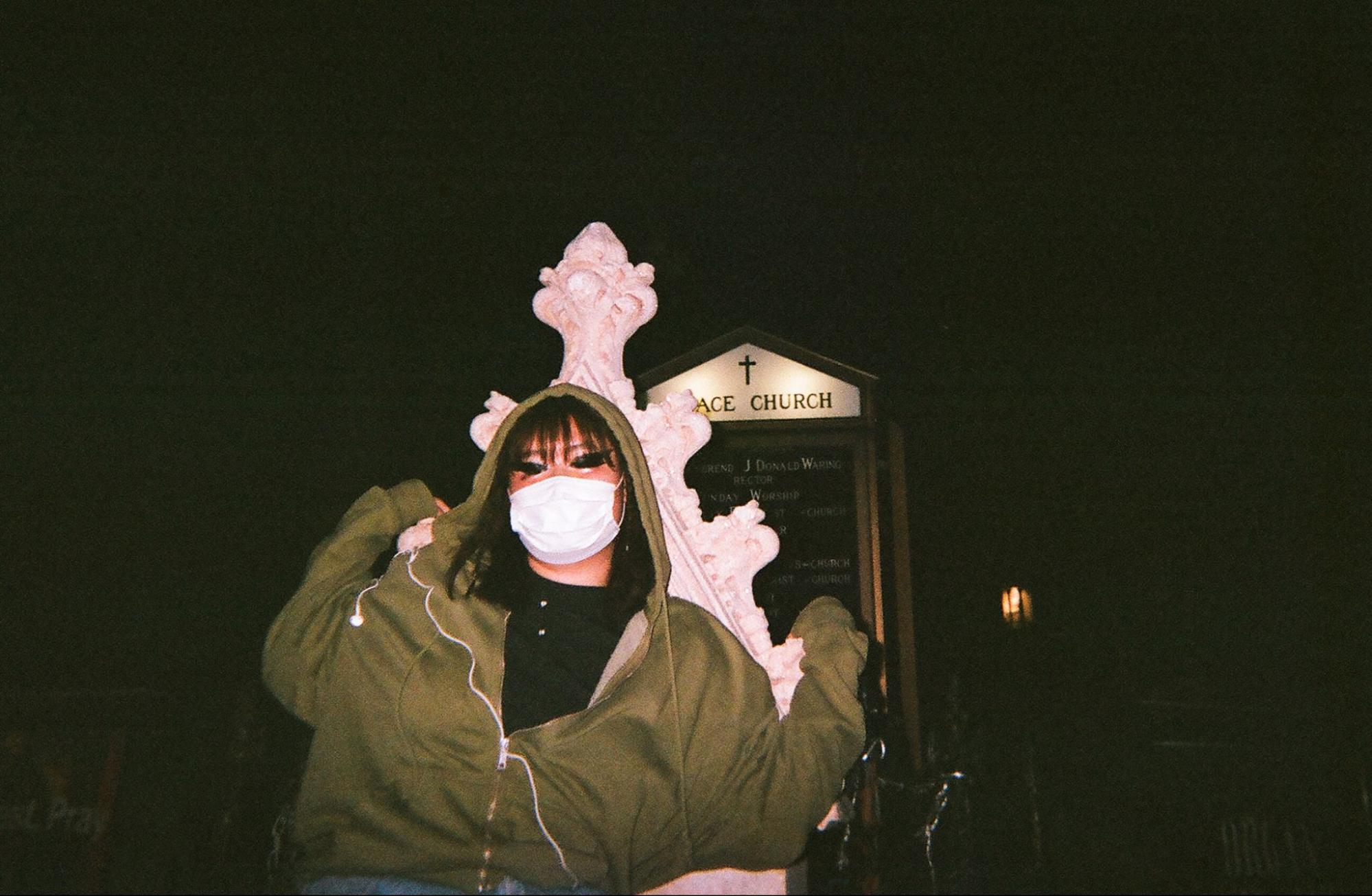 Margaret posing in front of Grace Church on Broadway, after midnight, COVID mask around her chin